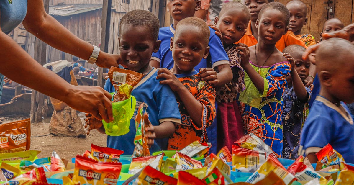 Home Joyful children receiving food supplies from a volunteer in an outdoor setting.